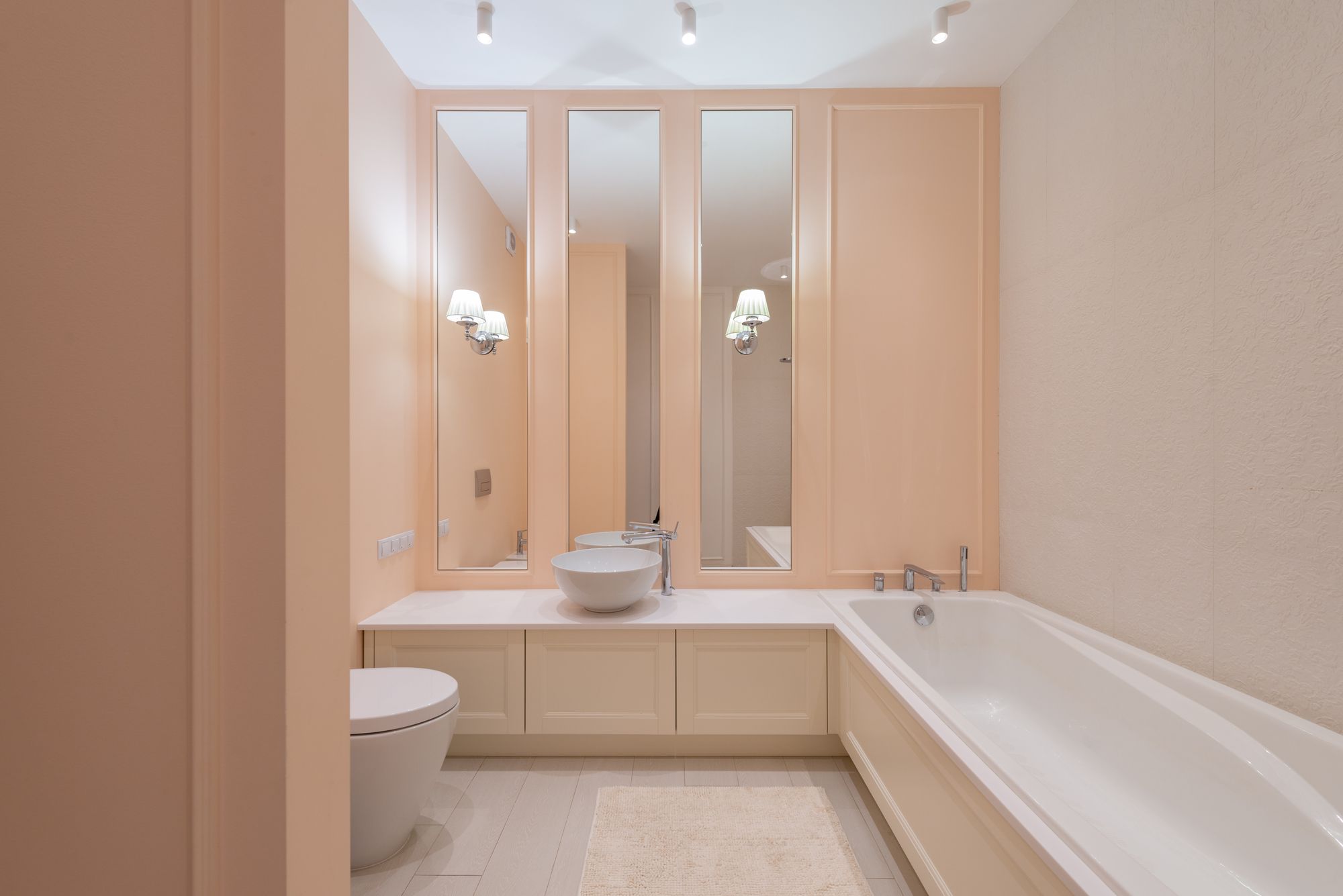 Light bathroom with beige walls, a bathtub and tall mirrors