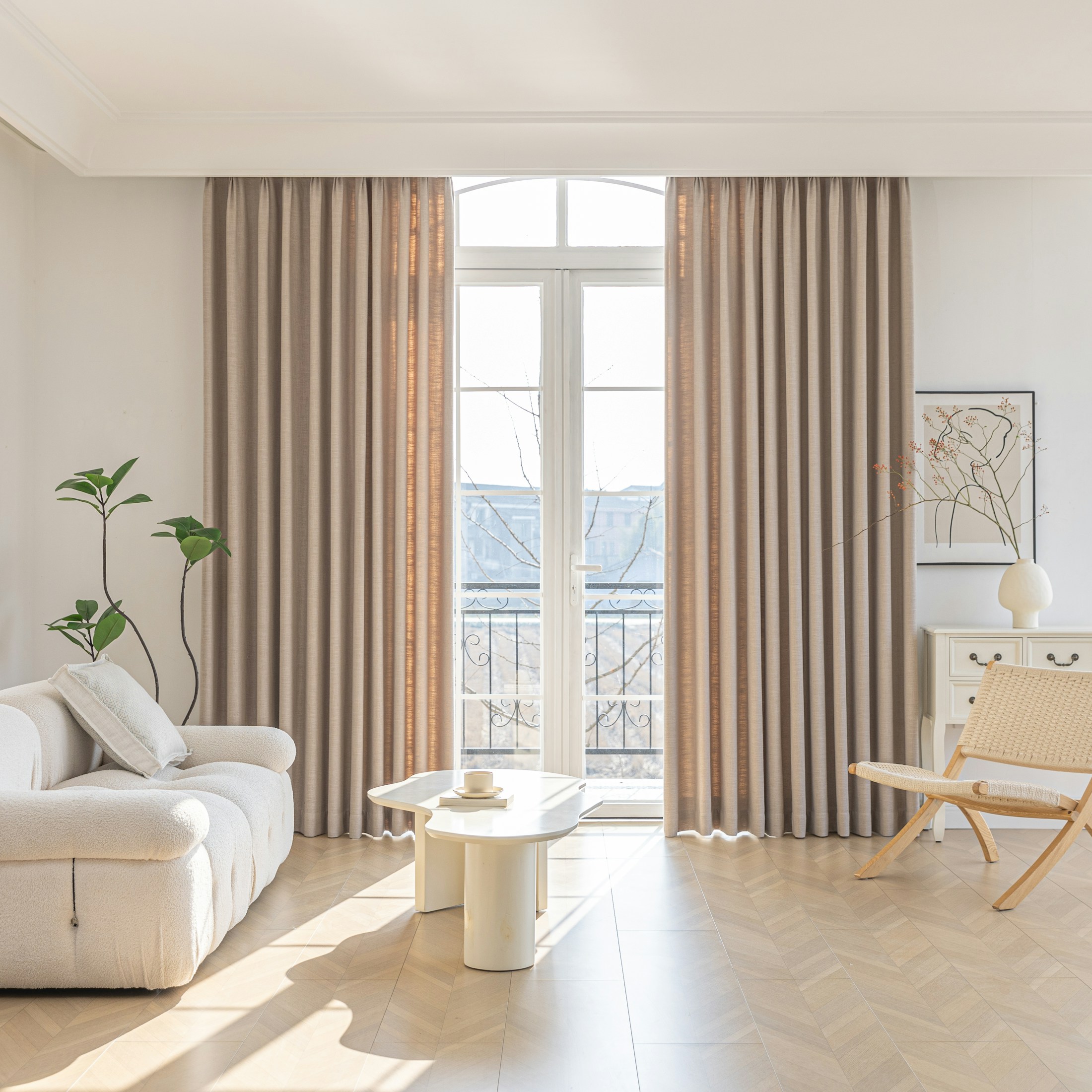 Sunlit living room with a sculptural ivory sofa, linen curtains and natural wood flooring
